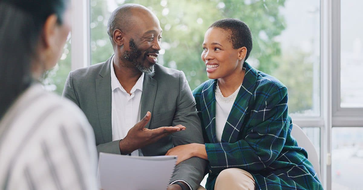 Smiling couple meeting with a financial advisor to discuss setting up a private foundation and long-term charitable giving strategy