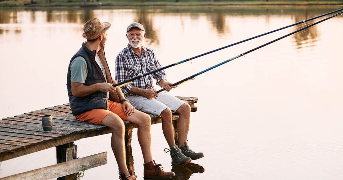 Happy senior man with no retirement regrets fishes with his son