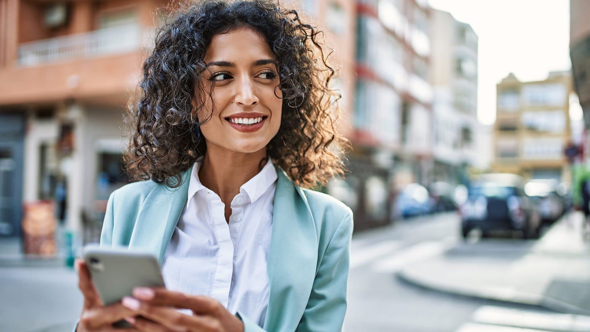 Young business woman wearing professional outfit in the city using smartphone