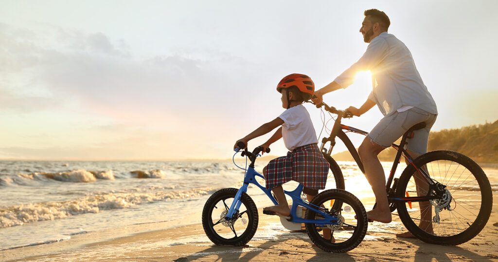 Father and son riding bikes on beach