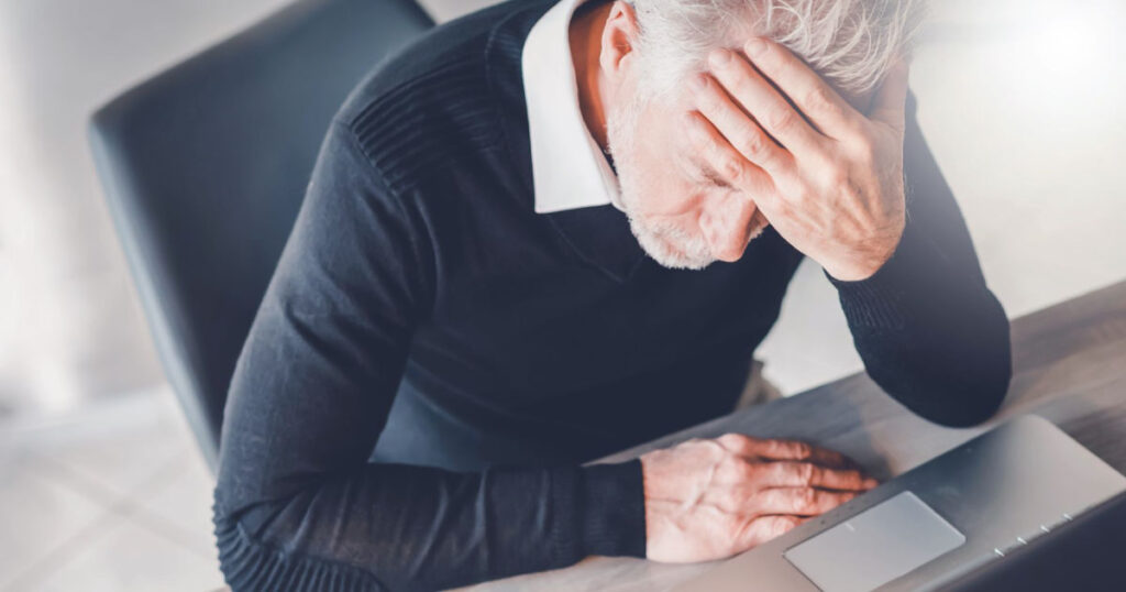 Frustrated man sitting in front of laptop