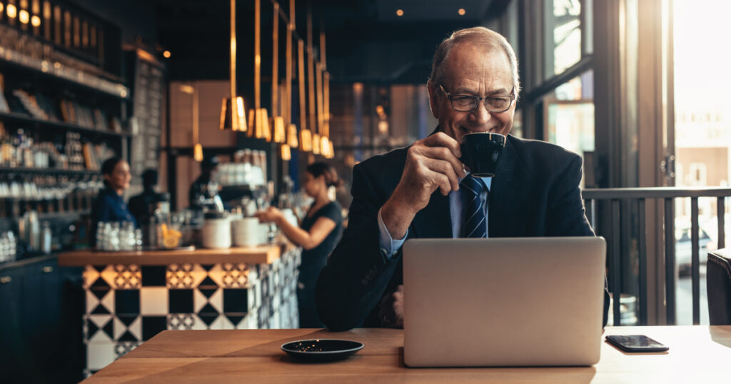 Older man in coffee shop with laptop