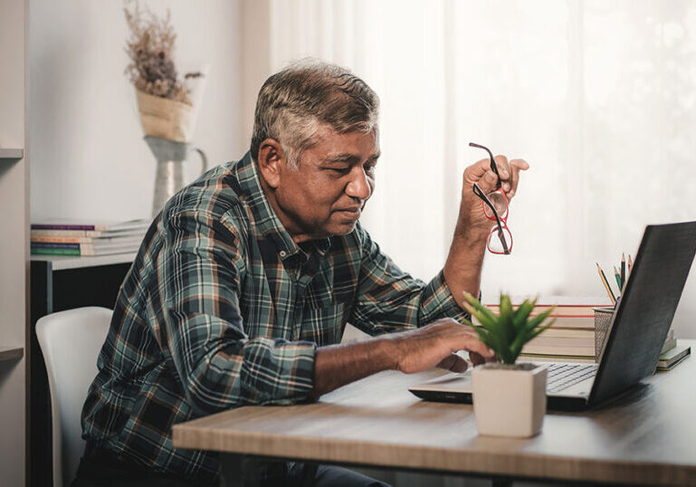 Mature man working on a laptop sitting at a desk.