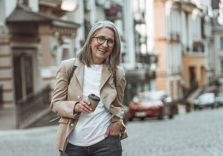 Happy senior woman holding to-go coffee cup