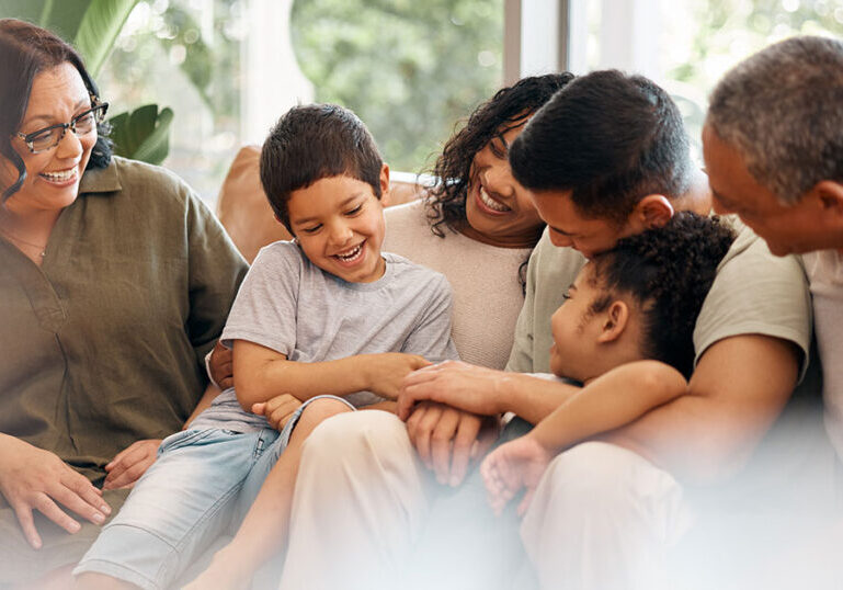 Multigenerational family sitting on a couch and smiling.