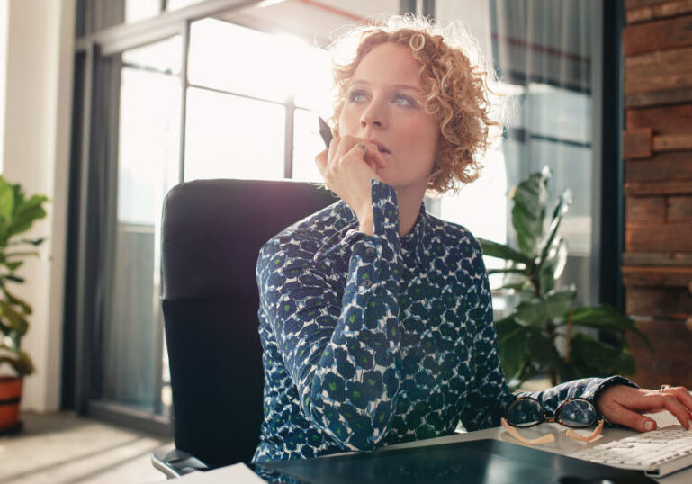 Woman sitting at computer lost in thought
