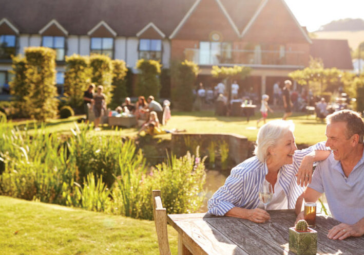 Senior couple sitting outside in the summer at outdoor pub.