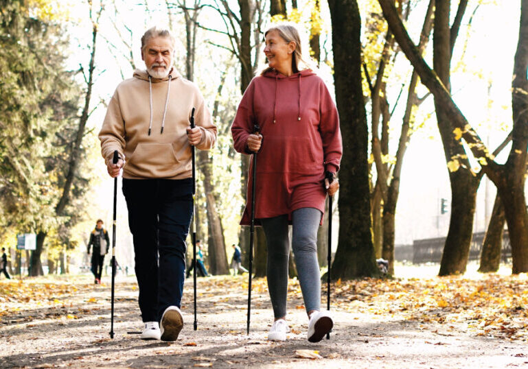 Senior couple with walking sticks hiking on trail