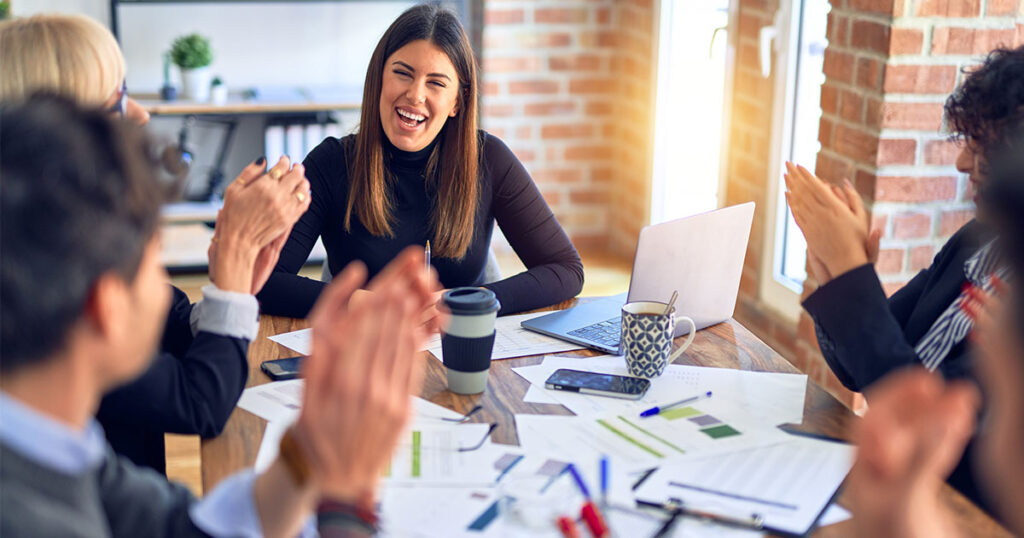 employees celebrating a team member on their accomplishment in a meeting