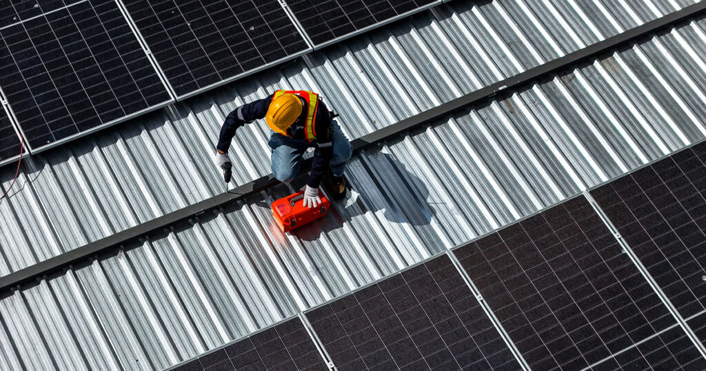 Worker installs solar panels on rooftop