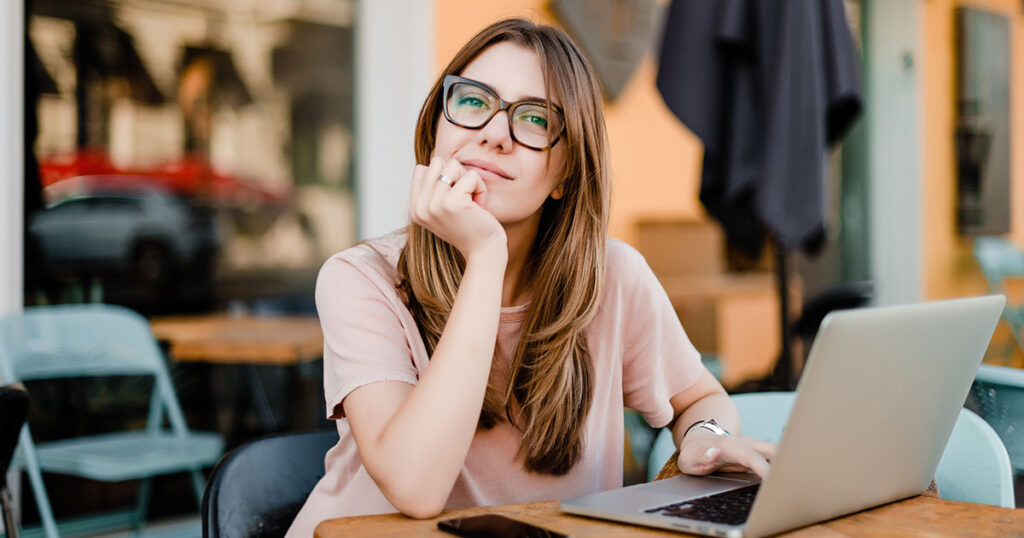 millennial woman with laptop sitting in cafe