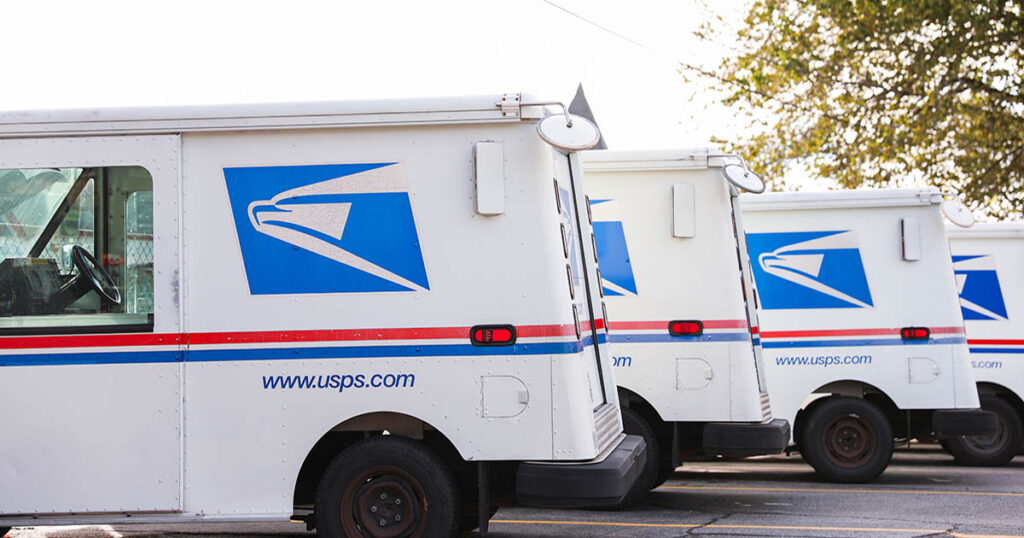 USPS mail delivery trucks parked in a row with official blue and red logo