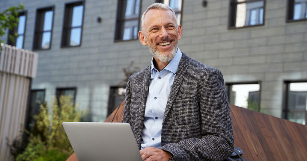 Smiling mature professional working on laptop outdoors