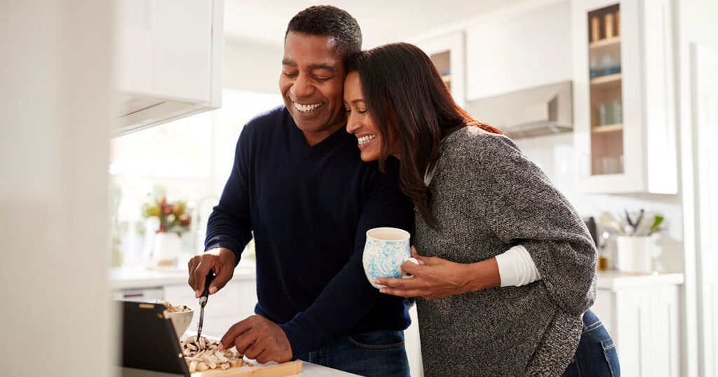 Midlife couple spending relaxed time together in the kitchen, reflecting a midlife reset and realigning time and money