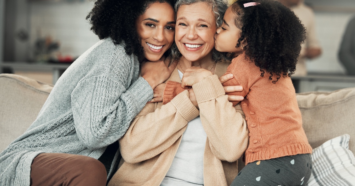 Grandmother sitting on a couch embracing two young family members, symbolizing multi-generational wealth planning support.