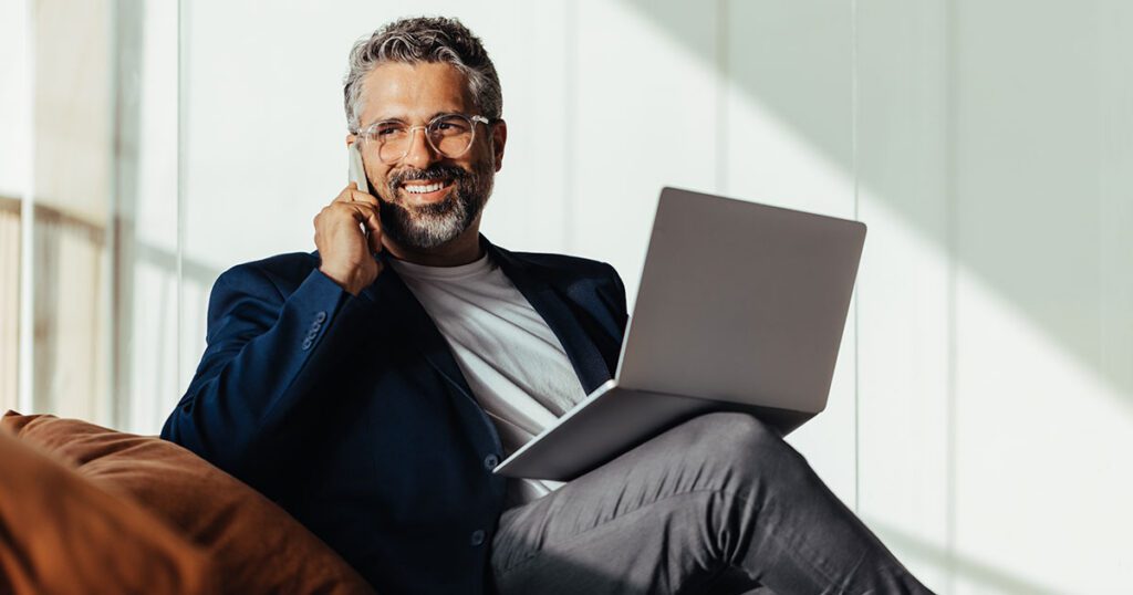 Ultra-high-net-worth individual sitting with a laptop and talking on the phone, representing customized family office-style services that coordinate complex wealth, planning and governance