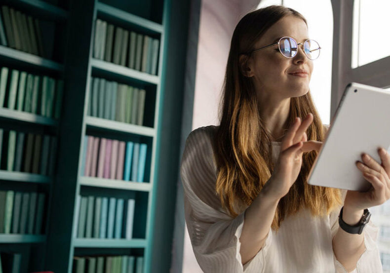 The financier is a woman working in an office reporting place writing a message using a tablet computer. A student with glasses in the library.