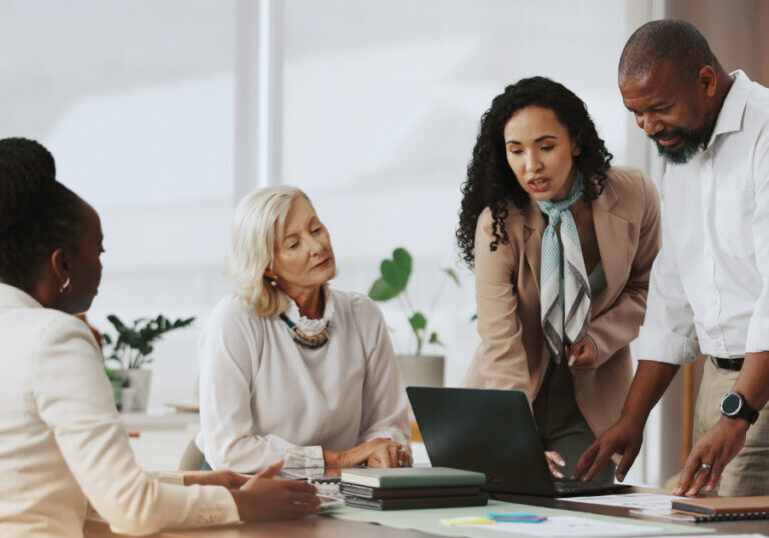 Business team collaborating around a laptop in a modern office, discussing strategy for a single family office.