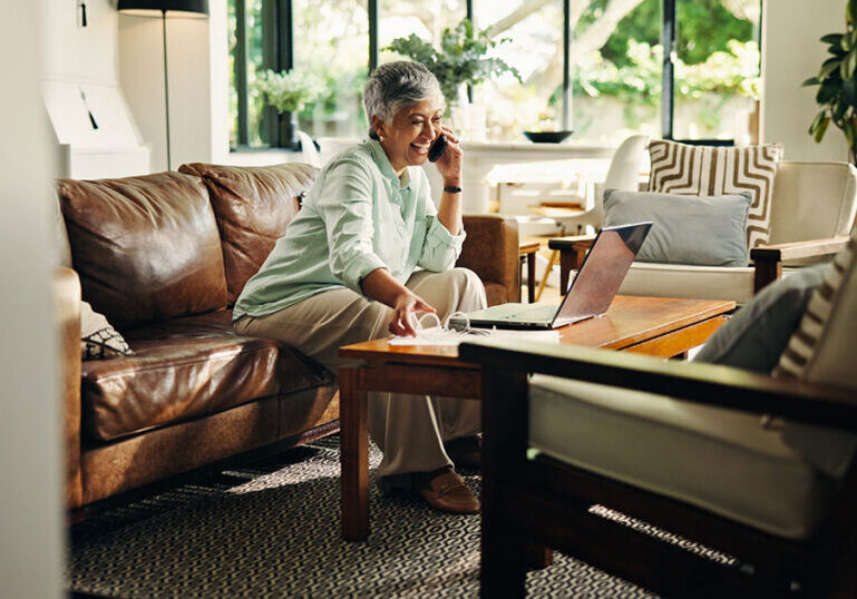 Woman reviewing her estate and tax planning on a laptop at home while talking on the phone about 2026 estate tax changes