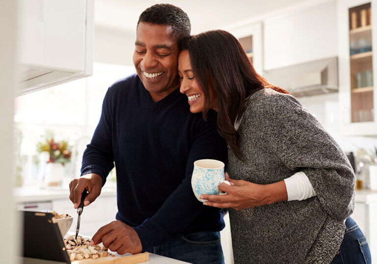 Midlife couple spending relaxed time together in the kitchen, reflecting a midlife reset and realigning time and money
