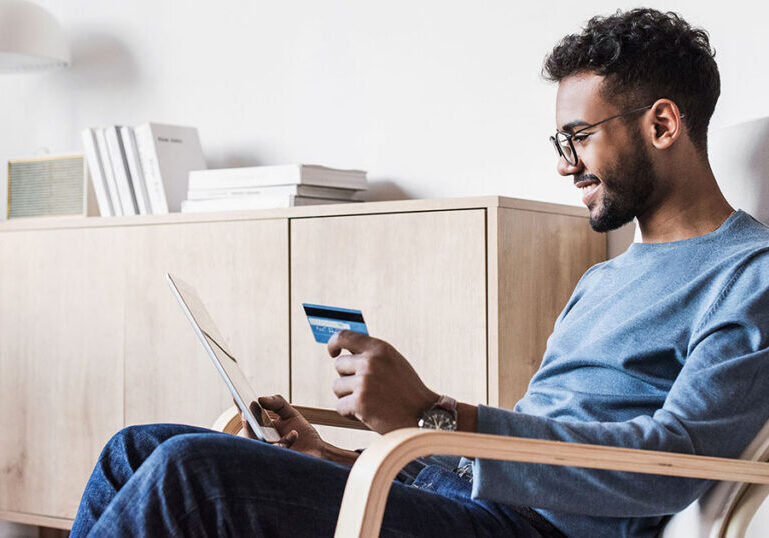 Man sitting at home reviewing his credit card and account details on a tablet, illustrating common credit card mistakes to avoid and how to use credit more wisely