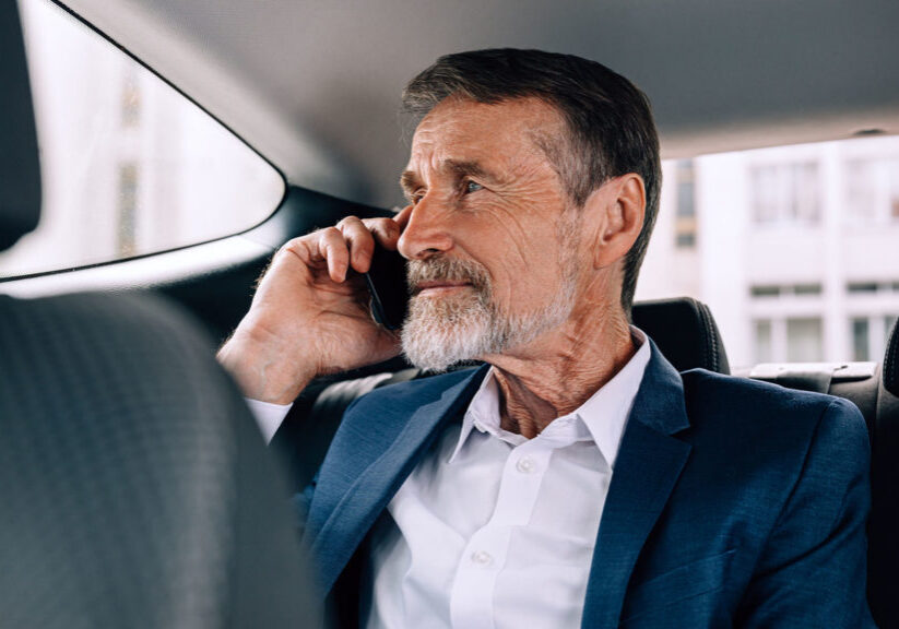 Pensive senior man holding a cell phone and looking out window