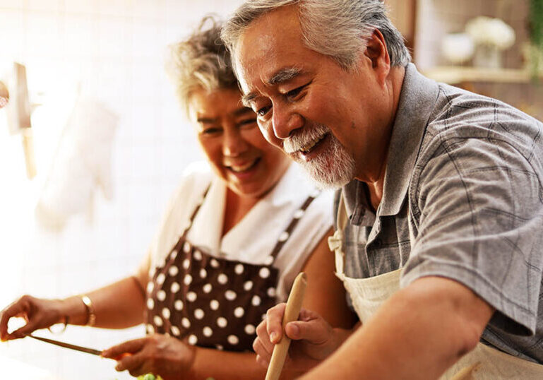 Happy couple in kitchen hopes their savings will last throughout retirement