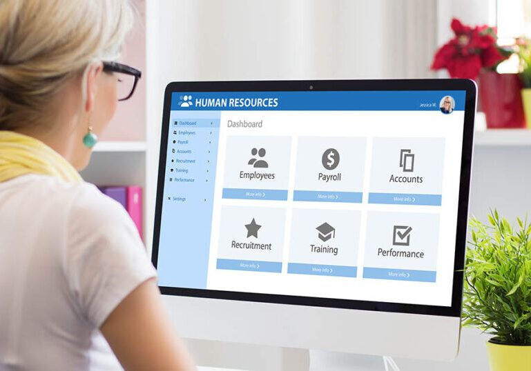 Woman works with dual human resources and payroll software on computer