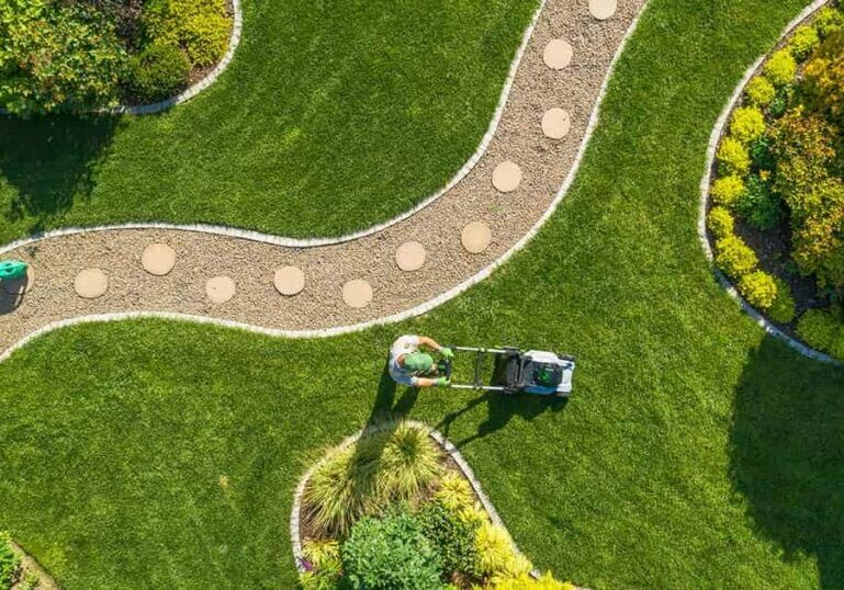 A professional landscaper mowing a neatly manicured lawn, illustrating how outsourcing routine work like accounting lets small business owners focus on growth.