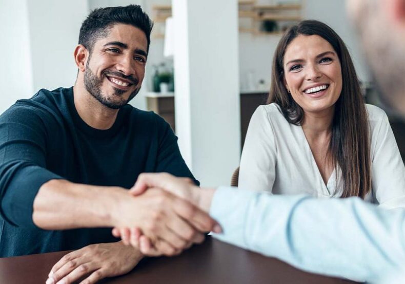 Shot of attractive real-estate agent shaking hands with young couple after signing agreement contract in the office.