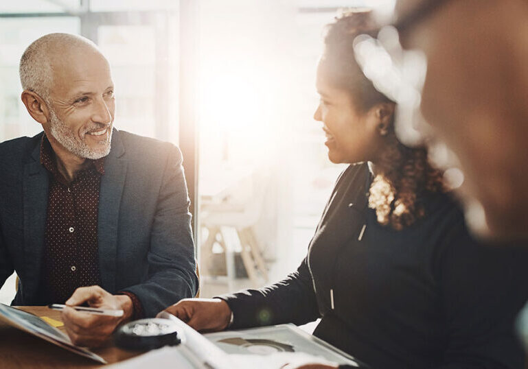 Wealth advisor meeting with ultra-high-net-worth clients in a bright modern office, reviewing tax and estate planning documents together at a conference table to discuss multigenerational wealth strategies.
