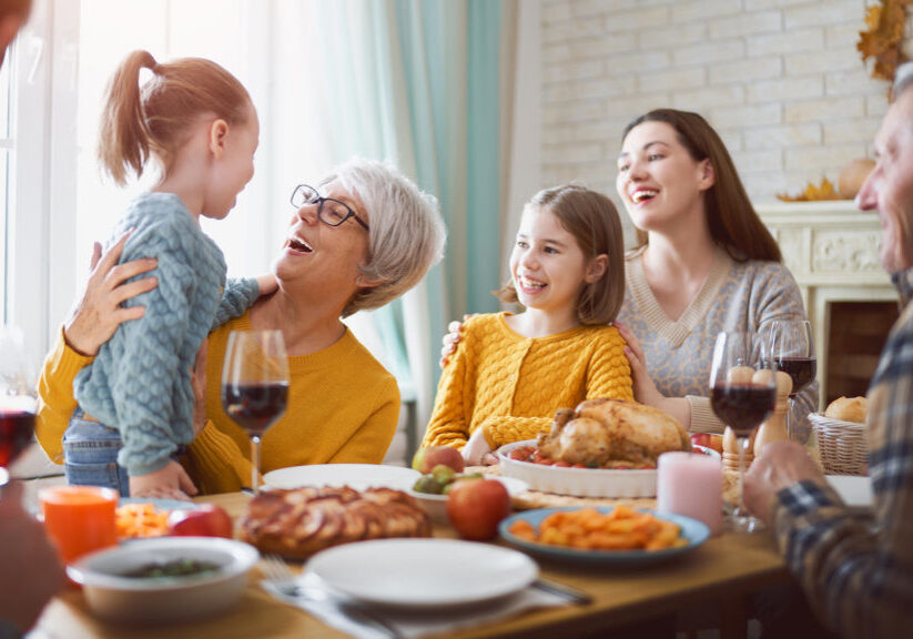 Happy Thanksgiving Day! Autumn feast. Family sitting at the table and celebrating holiday. Grandparents, mother, father and children. Traditional dinner.