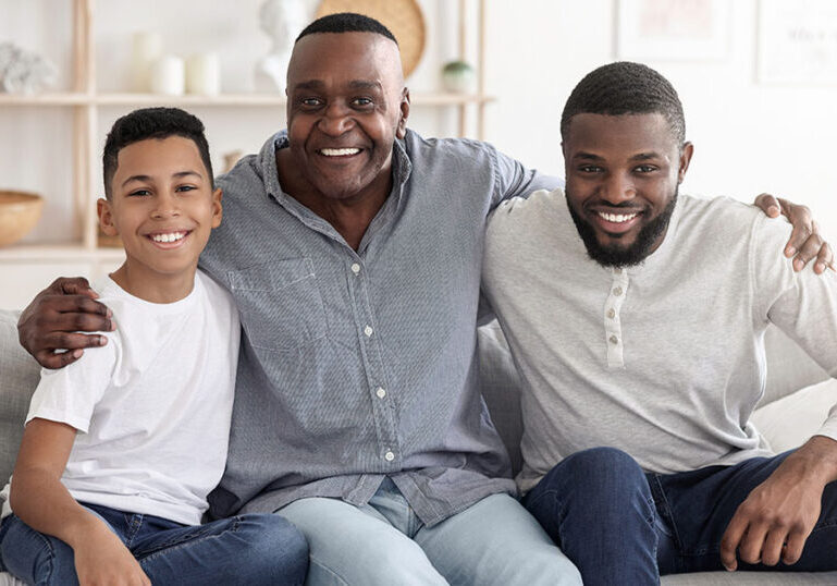 Happy African American Son, Father And Grandfather Bonding Together At Home, Hugging And Posing To Camera While Relaxing On Couch