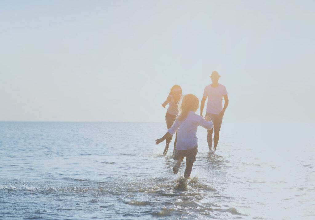 Happy young family having fun running on beach at sunset. Family traveling concept